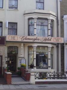 布莱克浦Gleneagles - Albert Road的建筑前有标志的商店