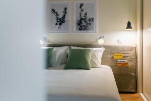 丰沙尔Three House Hotel的一间卧室配有一张带白色和绿色枕头的床