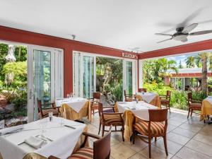 汉密尔顿皇家棕榈酒店 的餐厅设有白色的桌椅和窗户。