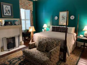 梅肯1842 Inn的一间卧室配有一张床、一把椅子和一个壁炉