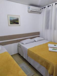 圣保罗豪斯佩达利亚伊皮兰加旅馆的配有黄色床单的客房内的两张床