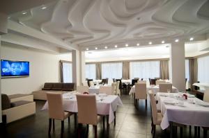 斯克拉斯卡波伦巴宜人气候酒店的餐厅设有白色的桌椅和天花板