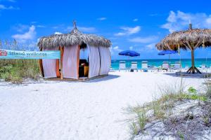 布雷登顿海滩Anna Maria Island Beach Palms 7A的海滩上的小小屋,配有椅子和遮阳伞