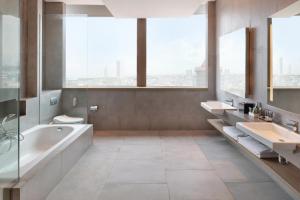 雅加达雅加达诺富特曼加达广场酒店的大型浴室设有2个水槽、浴缸和卫生间。