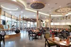 科威特Holiday Inn - Suites Kuwait Salmiya, an IHG Hotel的一间设有桌椅的餐厅,有坐在桌子上的人