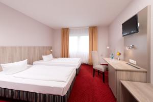法兰肯塔尔ACHAT Hotel Frankenthal in der Pfalz的酒店客房配有两张床和一张书桌