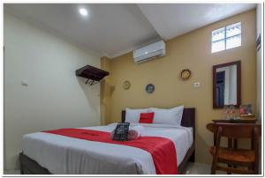 LaweanRedDoorz Syariah near Solo Square Mall的一间卧室配有一张带遥控器的床