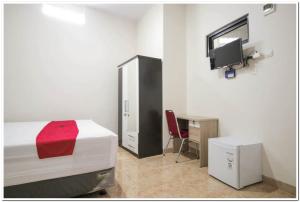 雅加达RedDoorz Syariah @ Jatinegara的一间卧室配有一张床、一张书桌和一台电视。