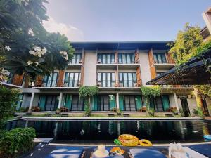 清迈Lamphu House Chiang Mai - SHA Extra Plus Certified的一座建筑前有池塘的酒店