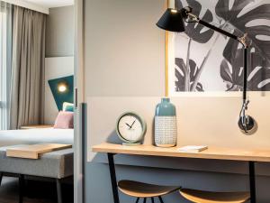 巴黎Aparthotel Adagio Paris Nation的客房设有一张带时钟和床的书桌