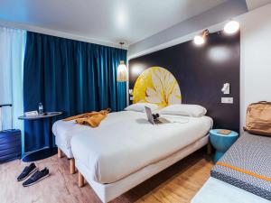 梅尔·莱斯·拜恩斯ibis Styles Le Treport Mers Les Bains的一间酒店客房,配有两张床,床上放着一只狗