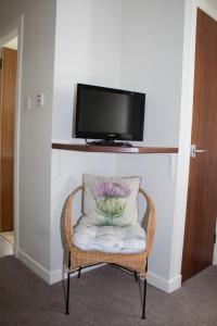 爱丁堡Whitecroft B&B的一张带枕头的椅子和墙上的电视