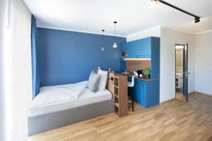 乌尔姆Brera Serviced Apartments Ulm的一间卧室设有蓝色的墙壁和一张带书桌的床。