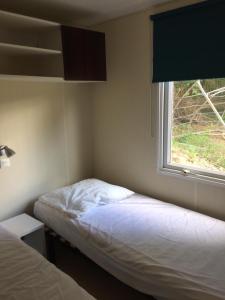 日安Camping Bois-Girault的一间小卧室,配有两张床和窗户