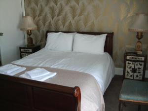 巴茅思Bluebells guest house的一间卧室配有一张带两盏灯和一把椅子的床。