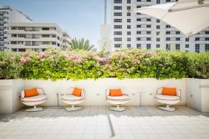 迈阿密海滩Berkeley Shore Hotel的庭院里摆放着一排带橙色枕头的椅子