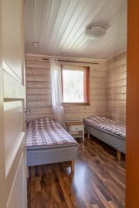 Korkeakoski库尔塔拉平房旅馆的配有木墙和窗户的客房内的两张床