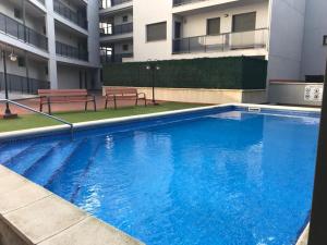 安波拉Precioso apartamento cerca de la playa的一座带长椅的建筑里的大型蓝色游泳池