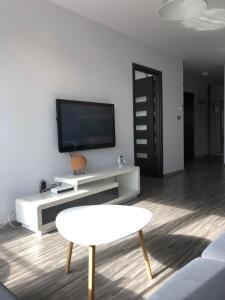 绿山城Apartament Ptasia的客厅配有电视和白色桌子。