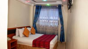 内罗毕Sheratton Regency Hotel Nairobi的一间卧室配有床和蓝色窗帘的窗户