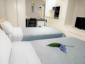 济州市ARA Palace Hotel的酒店客房设有两张床,床上有一朵花