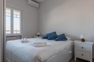 马德里MintyStay - Paseo de las Delicias的卧室配有白色床、蓝色枕头和窗户