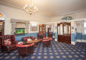 滨海韦斯顿皇家酒店 的客厅配有椅子、桌子和吊灯。