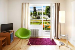 巴登公园酒店的客厅设有绿椅和大窗户