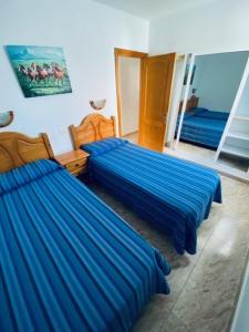 英格兰海滩桑德拉公寓的配有蓝色床单的客房内的两张床