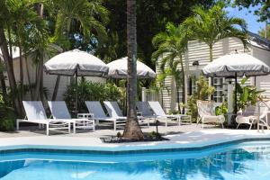 基韦斯特Lighthouse Hotel - Key West Historic Inns的房屋旁的游泳池配有椅子和遮阳伞