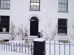 林顿St Vincent Guest House的坐在房子前面的围栏上的猫
