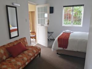 布雷达斯多普6 on Kloof Guest House的一间卧室配有一张床、一张沙发和一个窗口
