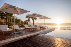 奥帕提亚Ikador Luxury Boutique Hotel & Spa的游泳池畔甲板上的一排椅子和遮阳伞