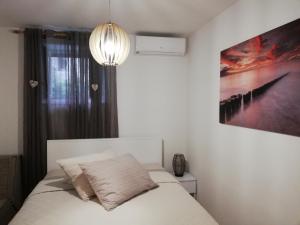 斯普利特Studio Apartman Lenka的卧室配有白色的床和墙上的绘画作品