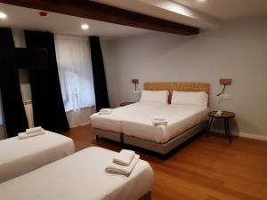 利亚内斯Hotel Puerto de Llanes的一间设有两张床和一张带两盏灯的桌子的房间