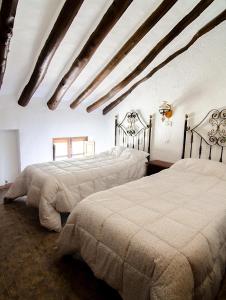 阿尔奇多纳科尔蒂霍安泽米格雅度假屋的一间卧室设有两张床和横梁天花板。