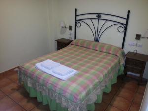 Alcaracejos拉斯特雷斯霍塔斯旅舍的一间卧室配有一张带铺着平底毯子的床和两张桌子。