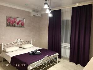 阿克托比Hotel Barhat Аktobe的一间卧室配有一张带紫色窗帘的床和窗户。