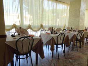 里米尼珍宝酒店的用餐室配有桌椅和白色窗帘