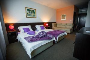 特里尔斯希沃特酒店的一间卧室配有一张带紫色床单的大床