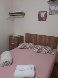 阿拉亚尔-杜卡布Varandas do Atalaia Suítes的一间卧室配有粉红色的床和毛巾