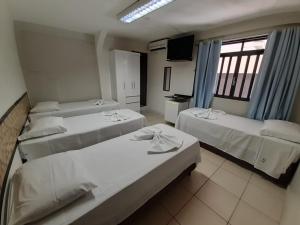 巴西利亚Pousada Damasco的一间设有三张床和电视的房间