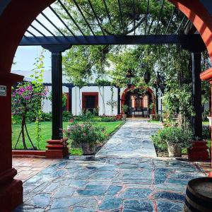 帕拉斯德拉富恩特Hotel El Farol的石头庭院,设有种有植物和鲜花的拱门