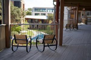 奥斯汀Hotel Magdalena的阳台配有三把椅子,设有游泳池