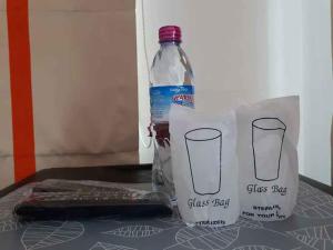 班武里府บ้านเล็ก รีสอร์ท的一瓶水和一张桌子上的袋子