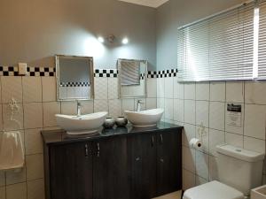 波切夫斯特鲁姆Graceland Guesthouse的一间带两个盥洗盆和卫生间的浴室
