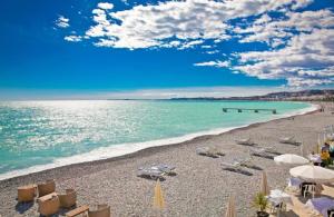 尼斯维克托瑞娜别墅家庭酒店的海滩上设有椅子和遮阳伞,还有大海