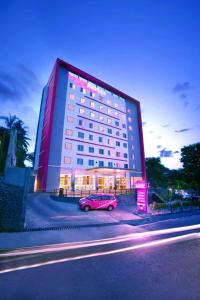茂物茂物帕德加加兰法维酒店的停在大楼前的粉红色汽车