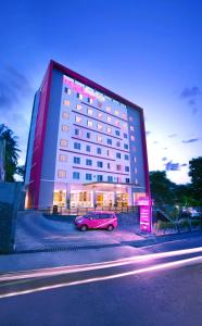 茂物茂物帕德加加兰法维酒店的停在大楼前的粉红色汽车