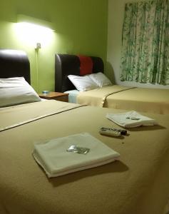 卢穆特Dindings Pantai Desair Apartment By DPD的酒店客房设有两张床和遥控器